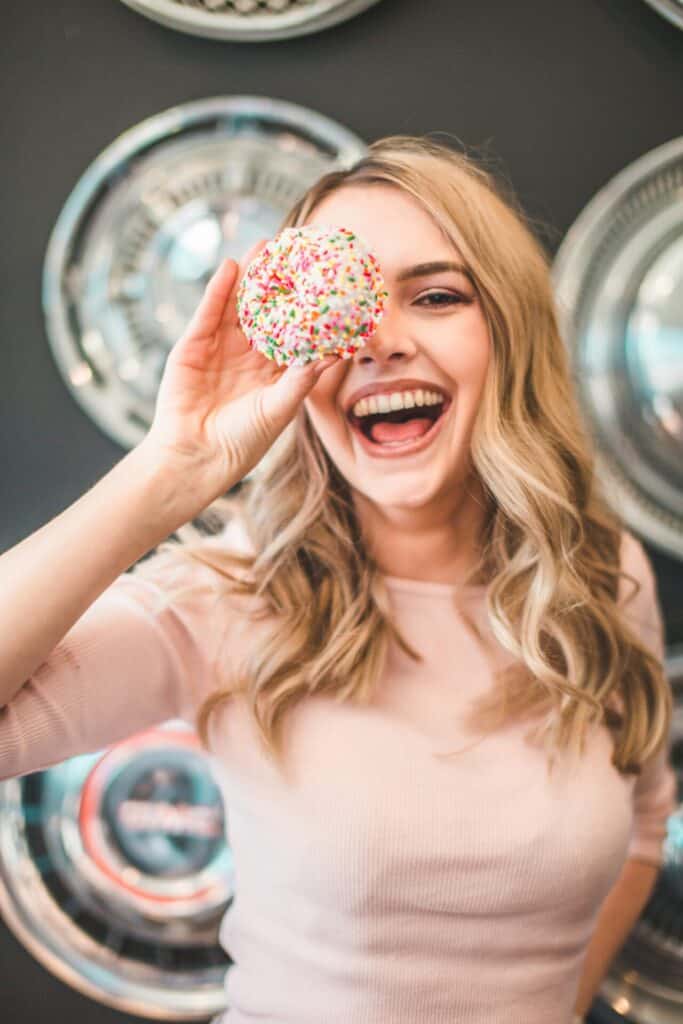 Fröhliche Independent Escort mit Donut in der Hand.
